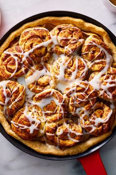 a pan filled with cinnamon rolls covered in icing