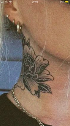 a woman's neck with a flower tattoo on the top and bottom part of her neck