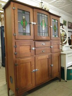 a wooden cabinet with stained glass doors in a room filled with other furniture and decor