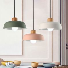 three lamps hanging from the ceiling above a table with plates and coffee cups on it