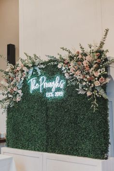 the wedding sign is surrounded by greenery and flowers on display at the reception table