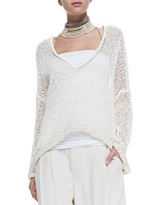 a woman is wearing white pants and a knitted sweater with a choker on her neck