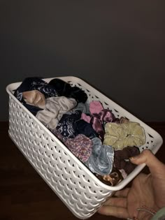 a white basket filled with clothes on top of a wooden floor