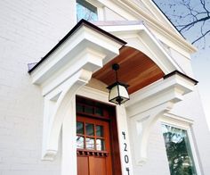 the front door of a white building with a light hanging from it's side