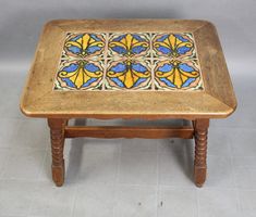 a wooden table with an intricate design on the top and bottom, sitting on a tile floor