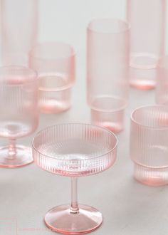 many pink glasses are lined up on a white surface with one empty glass in the middle