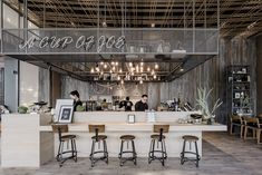 the interior of a restaurant with bar stools and lights hanging from the rafters