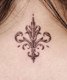 the back of a woman's neck with a fleur de lis tattoo on it