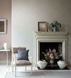 a living room filled with furniture and a fire place in front of a wallpapered wall