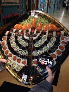 someone holding up a platter of sushi in front of an advertizer