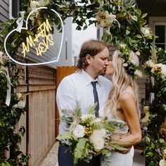 a man and woman kissing in front of a heart shaped neon sign that says we are married