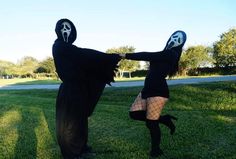 two people dressed up in costumes standing on the grass with their arms around each other