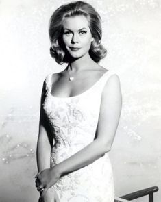 an old black and white photo of a woman in a dress posing for the camera