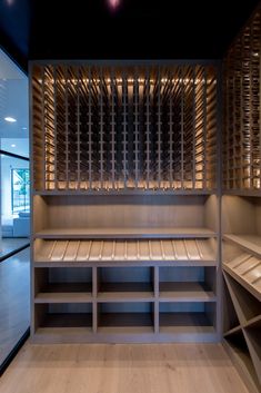 an empty walk - in closet with wooden shelves and glass doors on the walls, is lit by recessed lights