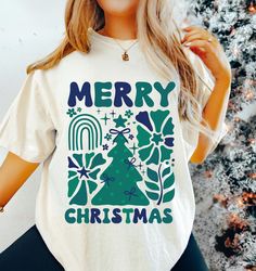 This Christmas T-shirt retro brings a nostalgic vibe to the holiday season. It is perfect for anyone looking to add a touch of vintage charm to their festive wardrobe. The unisex design makes it suitable for a wide range of buyers, from Christmas enthusiasts to those who appreciate unique holiday fashion. Ideal for Christmas parties, family gatherings, and holiday photos. Product features - Available in sizes S to 4XL for the perfect fit - Double-needle stitching for durability - Garment-dyed fa Xmas Tshirt Design, Vintage Xmas, Comfort Colors Tshirt, Christmas Tshirt, Festival Shirts, Christmas T Shirt, Holiday Shirts, Holiday Photos, Retro Christmas