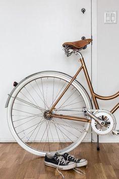 an old bicycle is sitting on the floor next to a pair of sneakers and a door