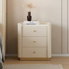 a nightstand with books and a vase on top