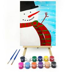 a snowman painting on an easel with paintbrushes in front of it