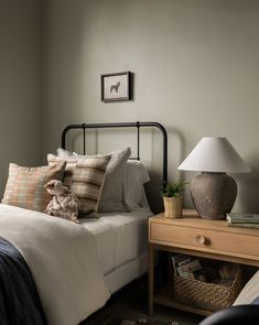 a bed room with a neatly made bed next to a night stand and a lamp