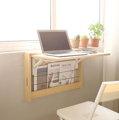 a laptop computer sitting on top of a wooden shelf next to a white chair in front of a window