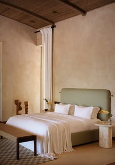 a bed with white sheets and pillows next to a window in a room that has beige walls