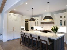 a large kitchen with white cabinets and marble counter tops, an island with four stools