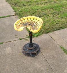 a yellow and black umbrella sitting on top of a metal pole next to a sidewalk