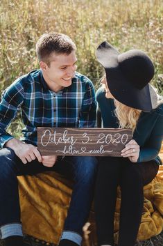 a man and woman sitting next to each other holding a sign