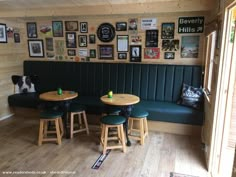 a restaurant with green booth seats and wooden tables in front of a wall full of framed pictures