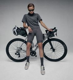 a woman sitting on top of a bike next to a helmet and bicycle bag in front of her