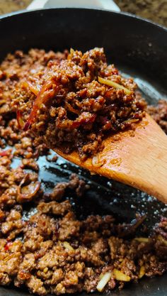 a wooden spoon stirring food in a skillet