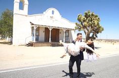 a man holding a woman in his arms while walking down the road