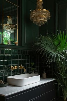 a bathroom with green tiles and a white sink under a large gold chandelier