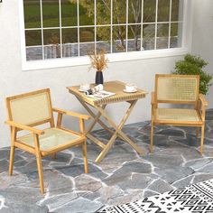 two chairs and a table in front of a window with a potted plant on it