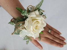 a white rose and greenery bouquet being held by someone's hand on their wedding day