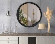 a round mirror is on the wall above a table with vases and other items