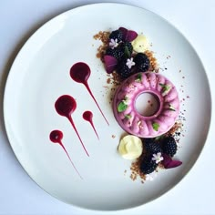 a white plate topped with a doughnut covered in berries and other fruit toppings