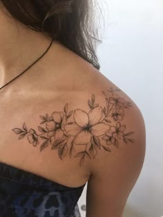 a woman's shoulder tattoo with flowers on her left arm and the upper half of her body