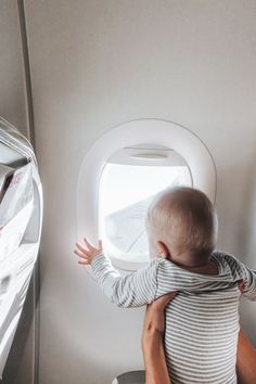 a man holding a baby looking out an airplane window