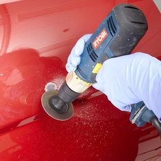 a person using a polisher on the hood of a red car while wearing gloves