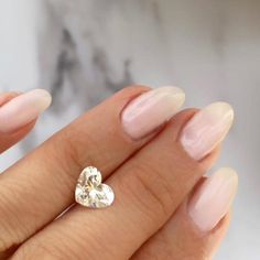 a woman's hand holding a heart shaped diamond