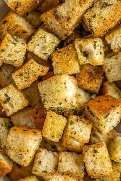 closeup of cooked bread cubes in a white bowl with seasoning sprinkled on top