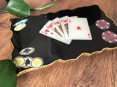 playing cards and chips are sitting on a black tray next to a green leafy plant