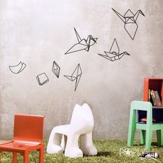 three chairs and a table in front of a wall with origami birds on it