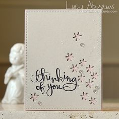 a card with the words thinking of you written in black ink on it, next to a figurine