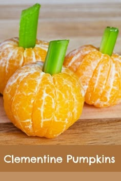 three peeled oranges with celery stems sticking out of them on a table