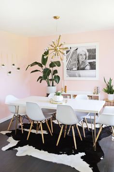 a dining room table with white chairs and a large plant in the middle of it