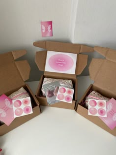 three open boxes with pink and white designs on the inside, one has a card in it