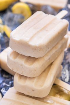 three popsicles stacked on top of each other with bananas and blueberries in the background