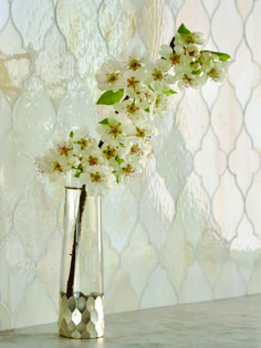 a silver vase with white flowers in it on a table next to a wallpaper